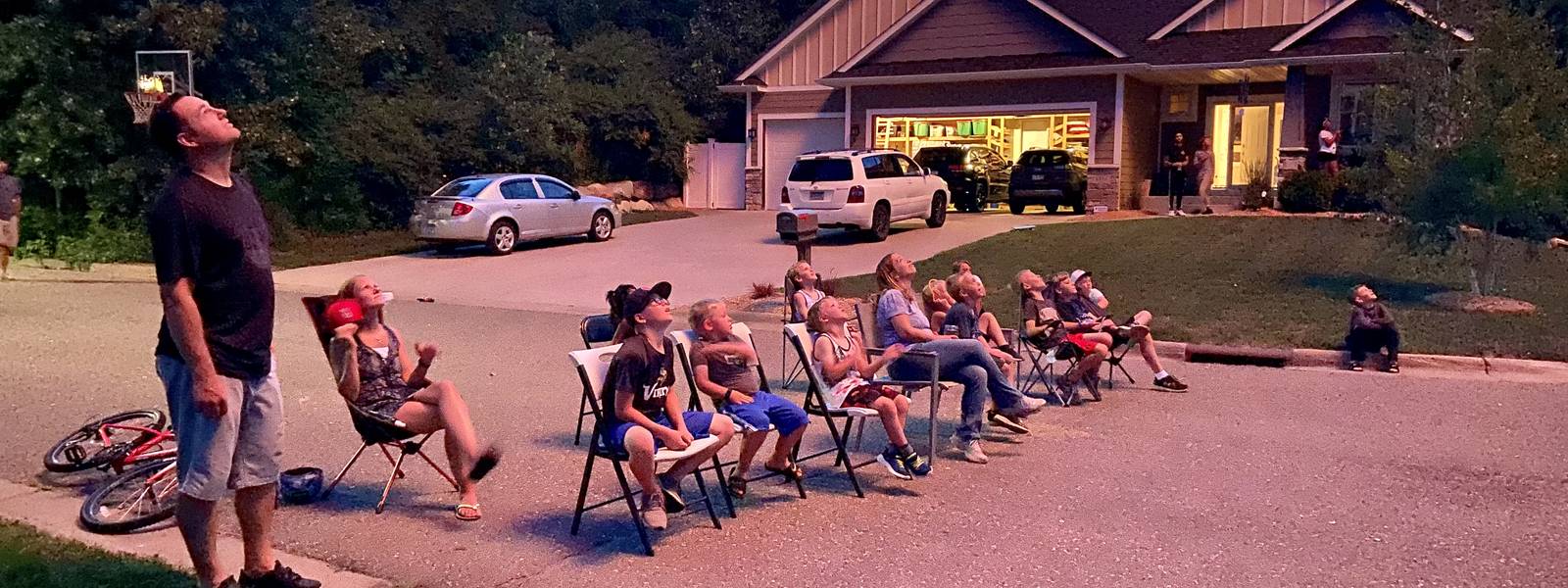 Neighbors watching the sky from lawn chairs in the street
