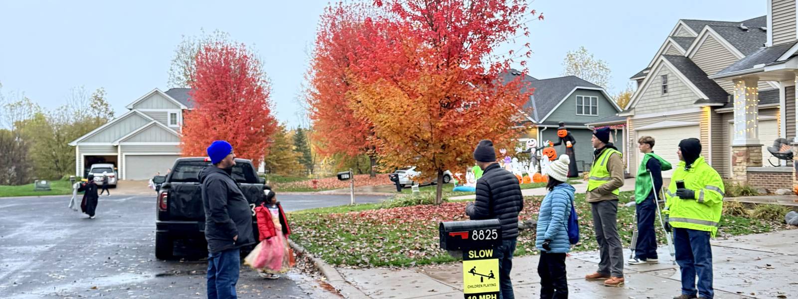 Neighbors on Halloween with red maples behind them