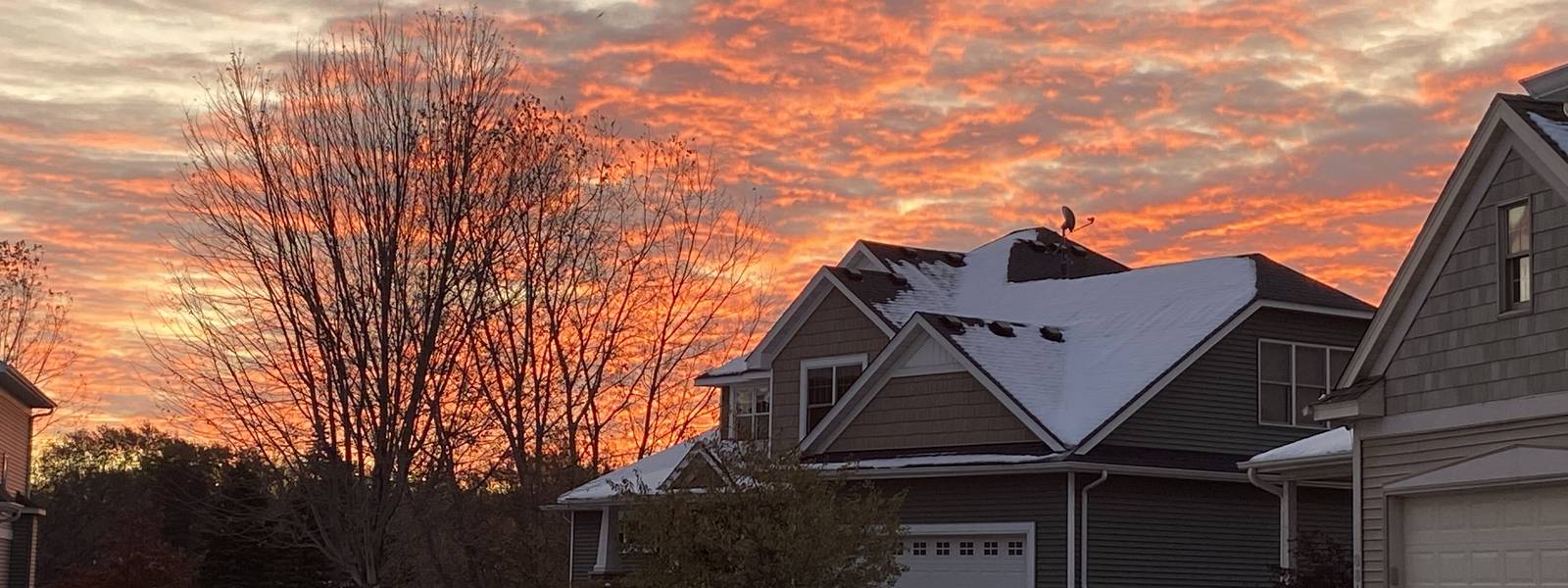 Orange sunrise over a snow-dusted roof