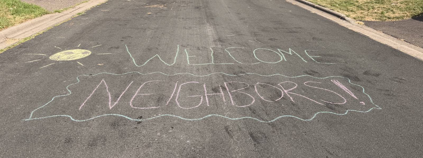 Welcome Neighbors written in chalk on the street for Night to Unite